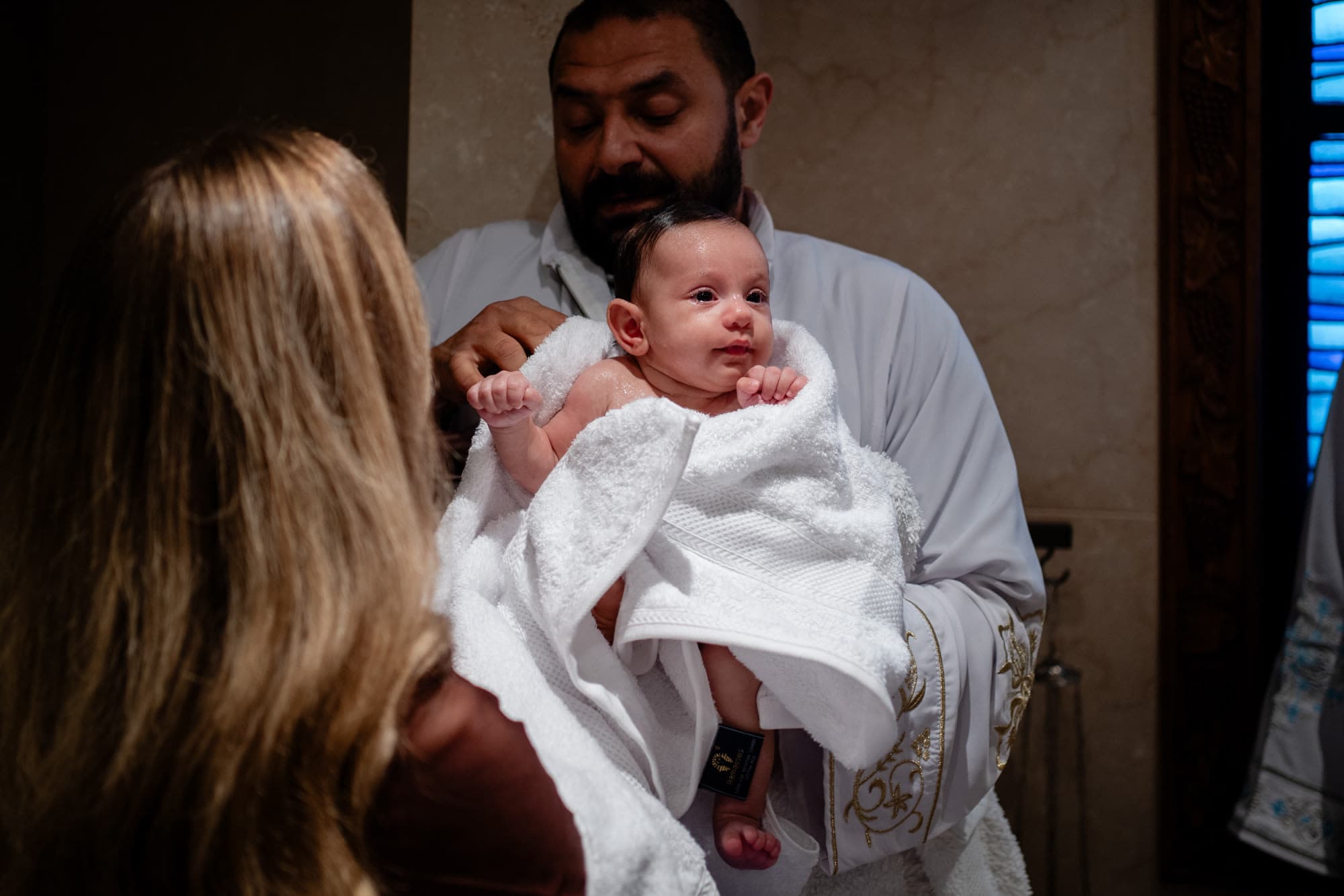 Godparents at a Sydney baptism ceremony, holding the child